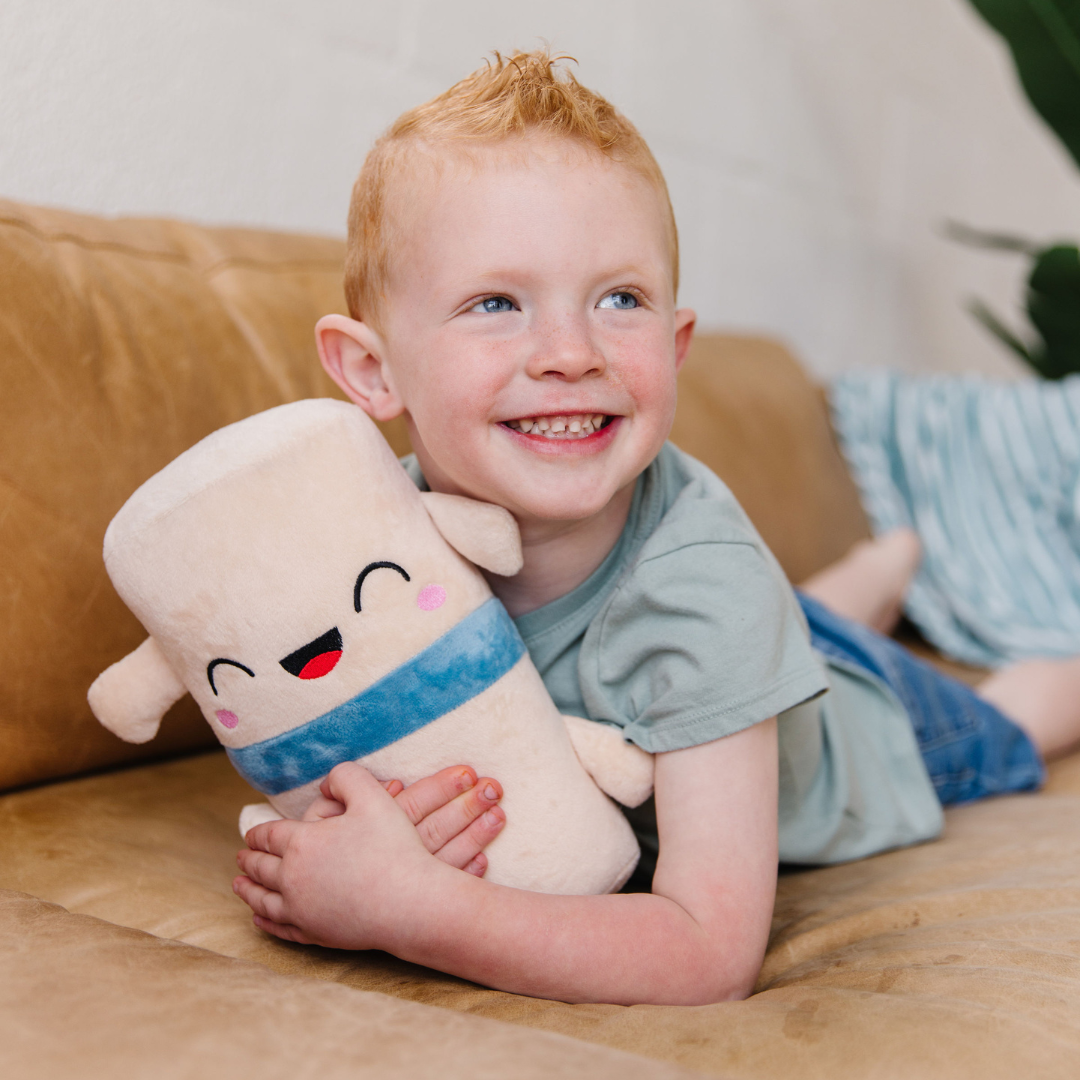 little boy hugging a nerdbugs spine plushie on the couch