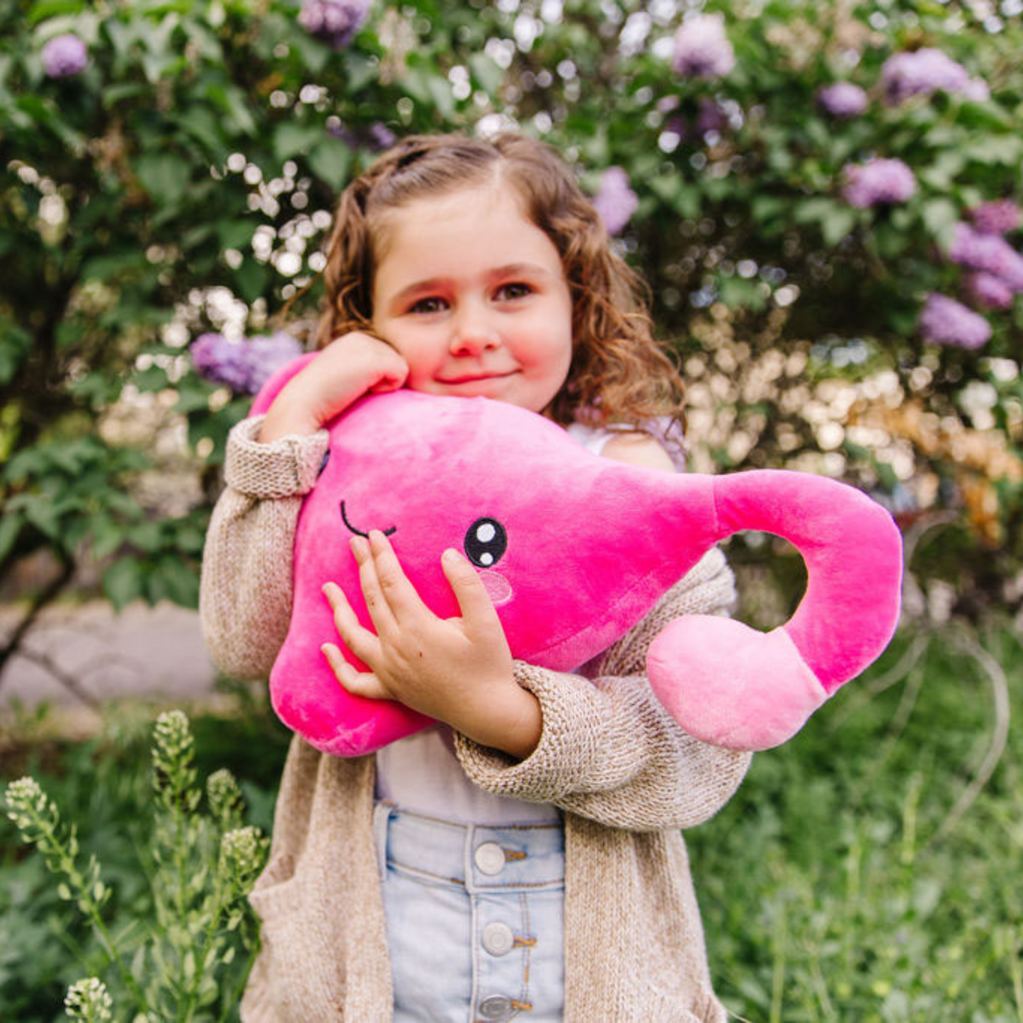 Smiling baby girl hugging a n uterus toy plushie
