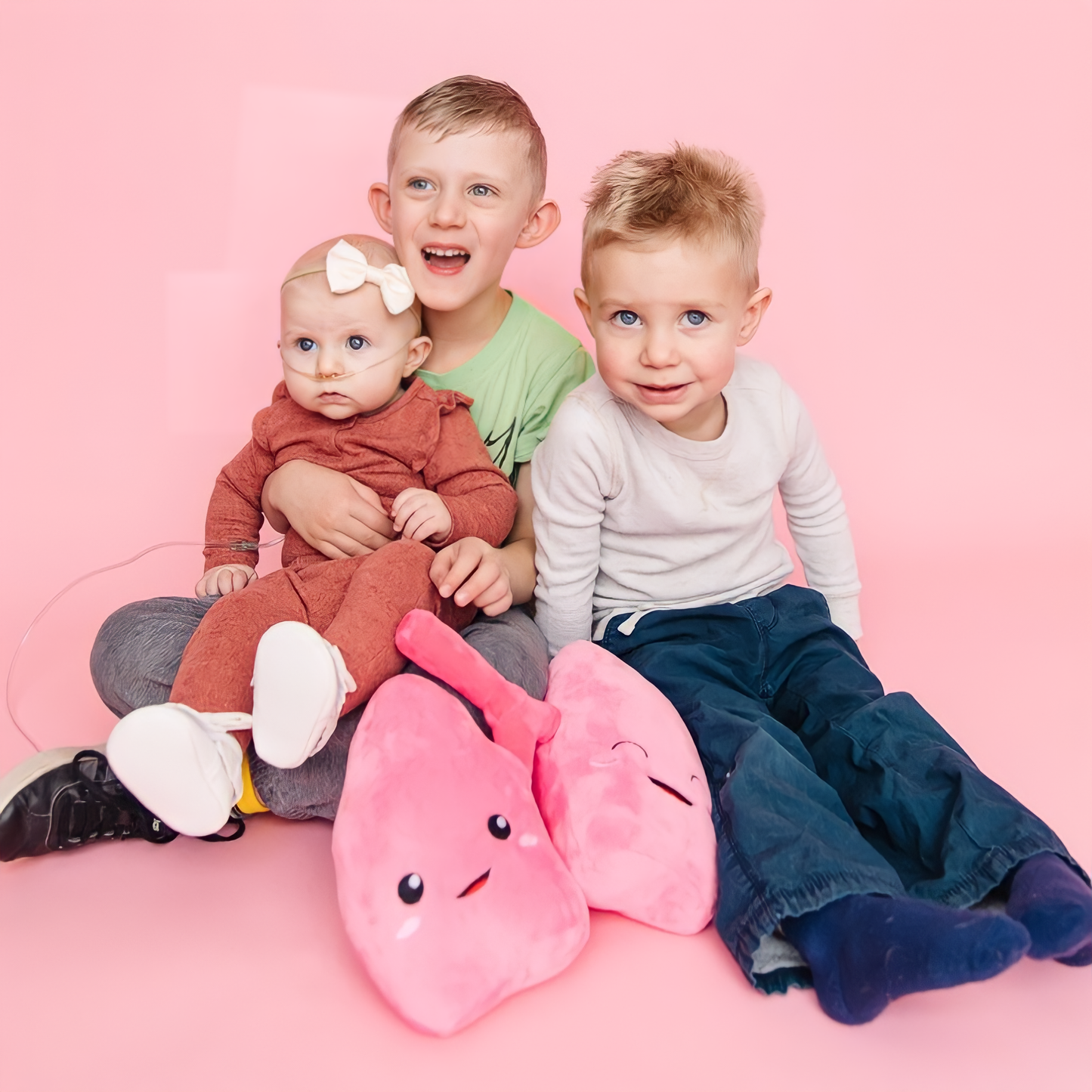 Siblings in pink background with lung toy plushie