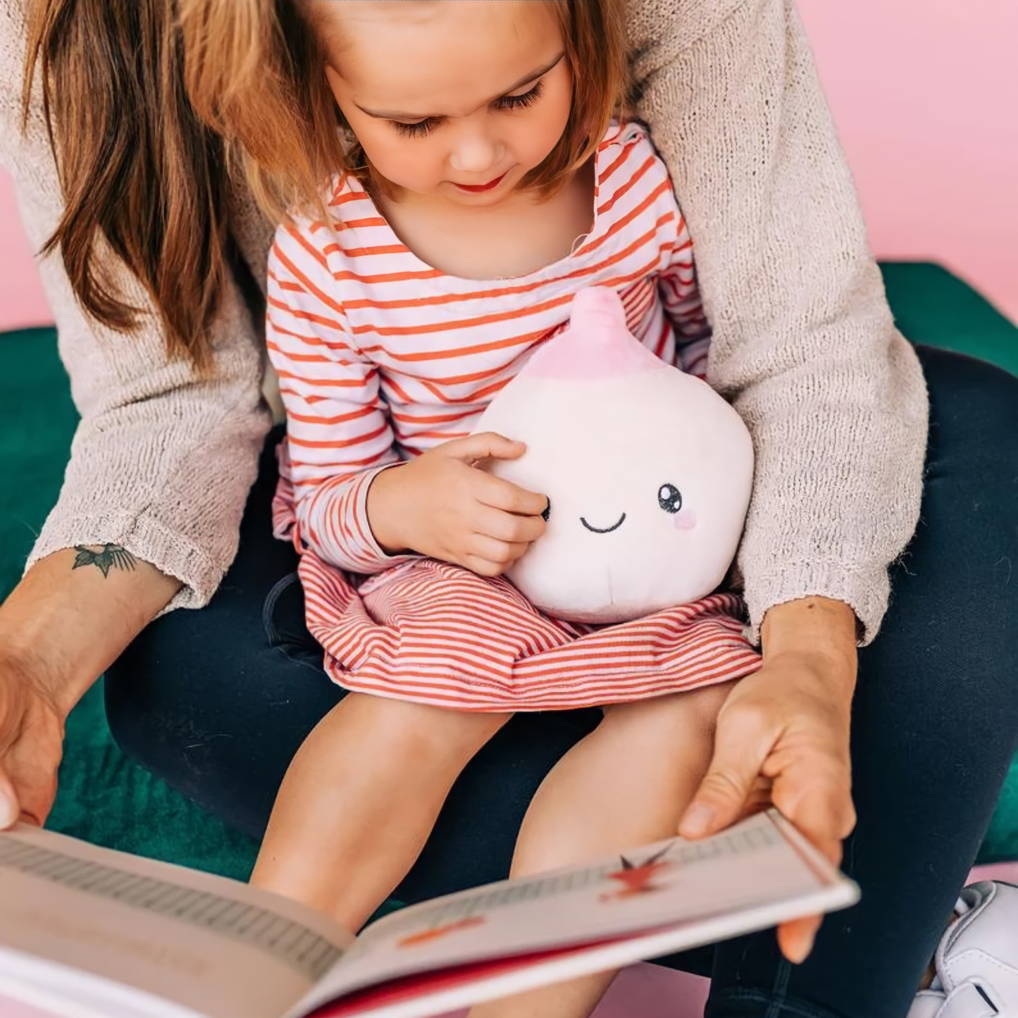 Mother and child reading a book while holding an ivory breast toy plushie