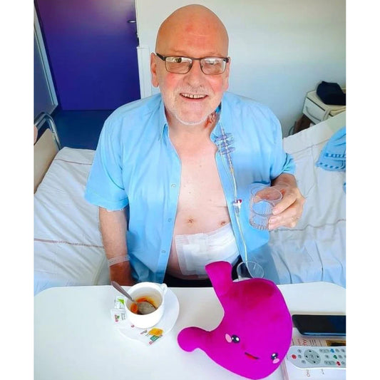 Man holding a glass water with Nerdbugs Stomach Organ Plushie infront of him
