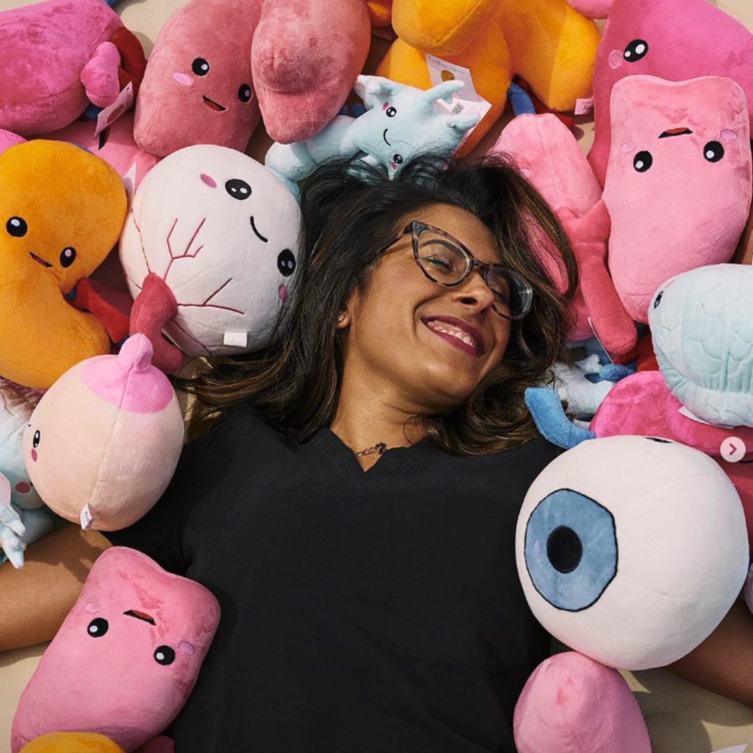 Dr. Ronak Mehta, CEO of Nerdbugs, laying surrounded with nerdbugs organ plushies