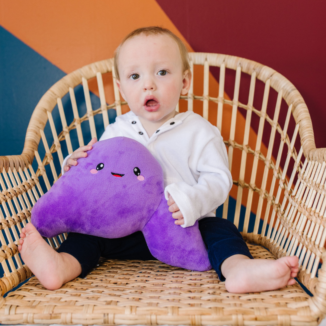 little boy sitting while holding a nerdbugs liver organ plushie