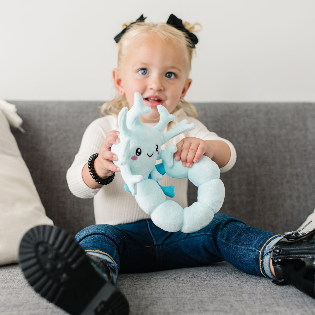 Little girl sitting while holding a nerdbugs spine plushie