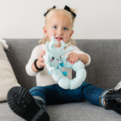 Little girl sitting while holding a nerdbugs spine plushie