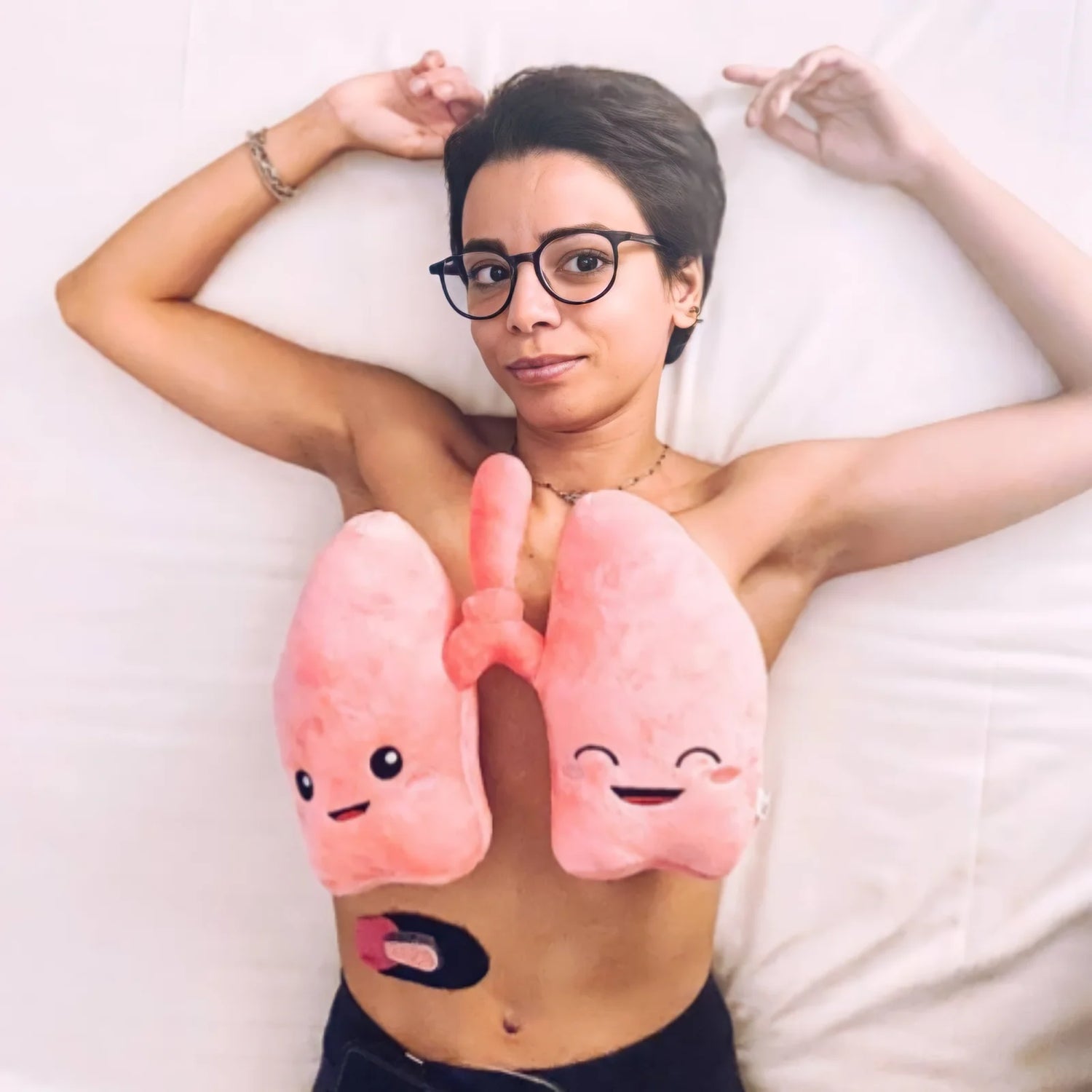 a woman lying down in bed with a lung plushie on her chest