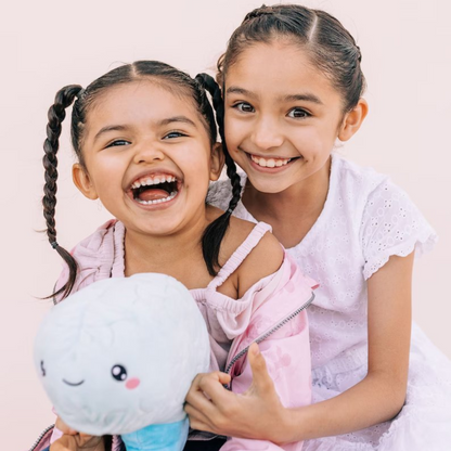 Two smiling girls holding a brain toy plushie