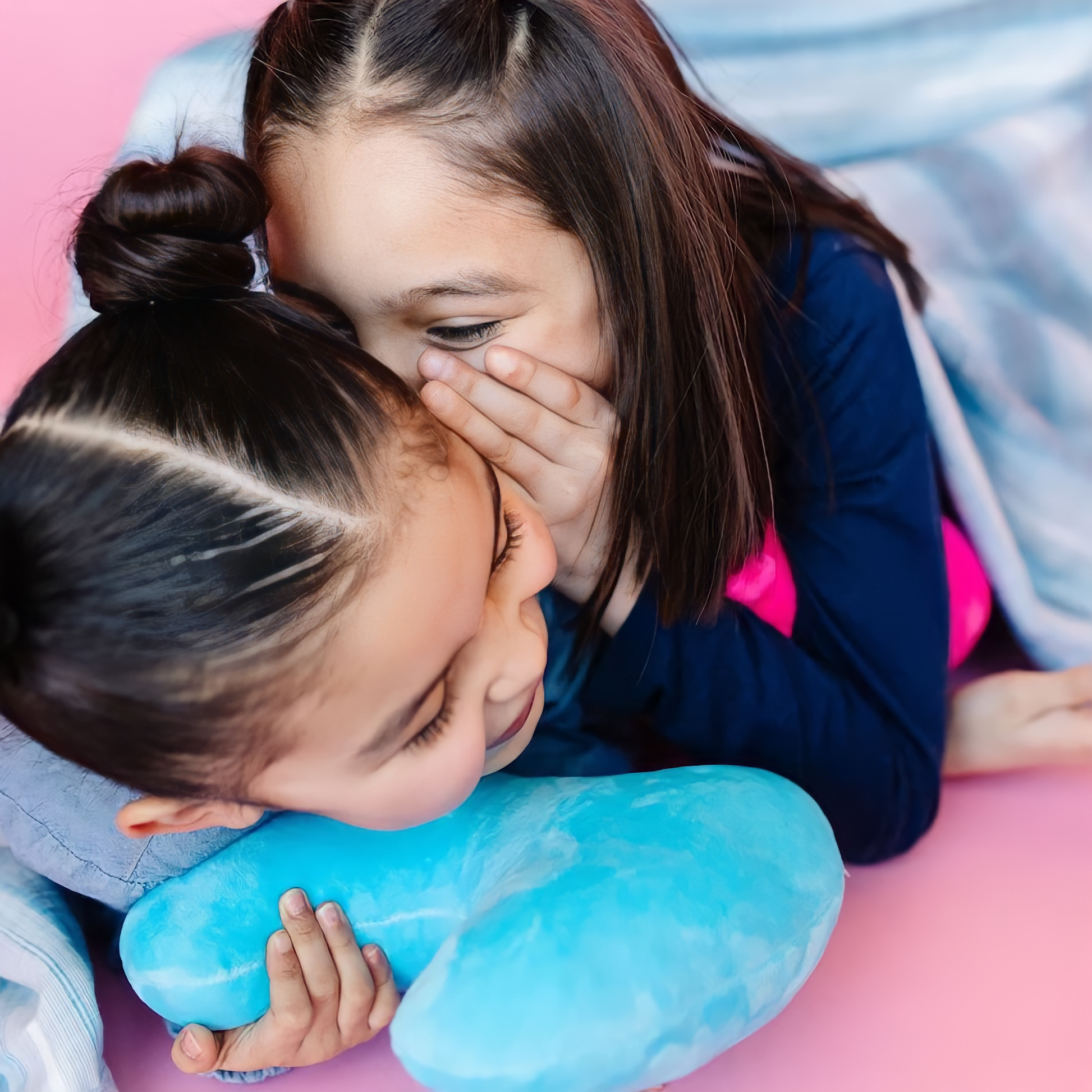 Girl whispering to her sibling while the other sibling holding a thyroid toy plushie