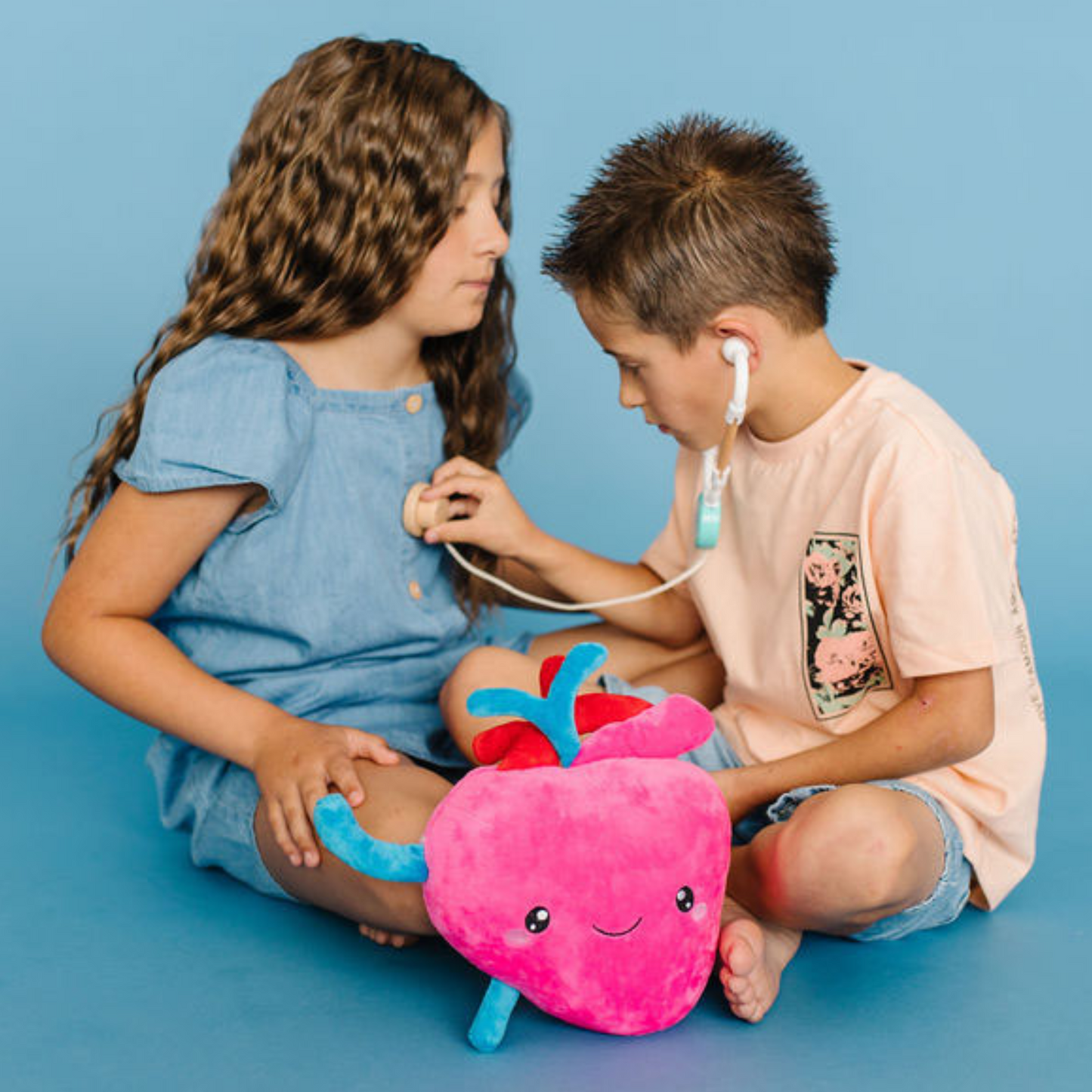 Baby girl and baby boy demonstrating a heart check with heart plushie in the front 