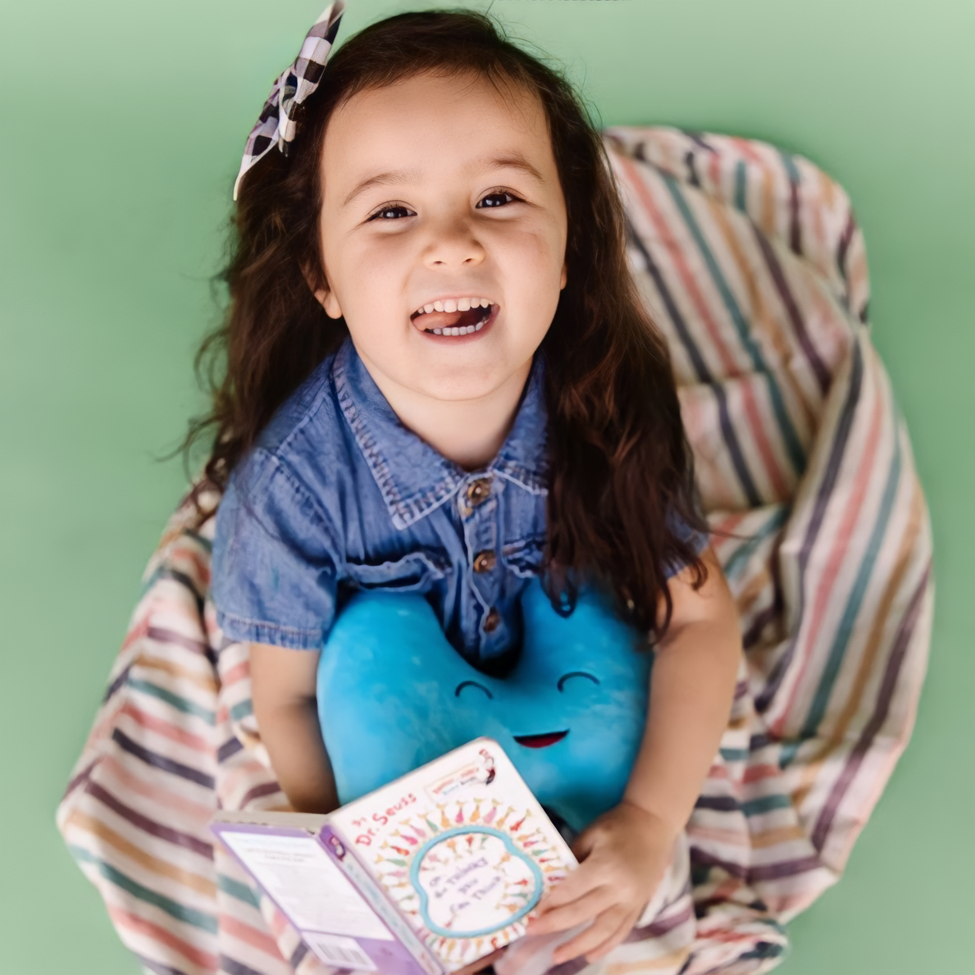 smiling baby girl holding a book and thyroid organ toy plushie