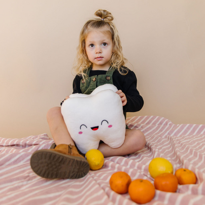 baby girl in sitting position holding a tooth plushie with orange and lemons